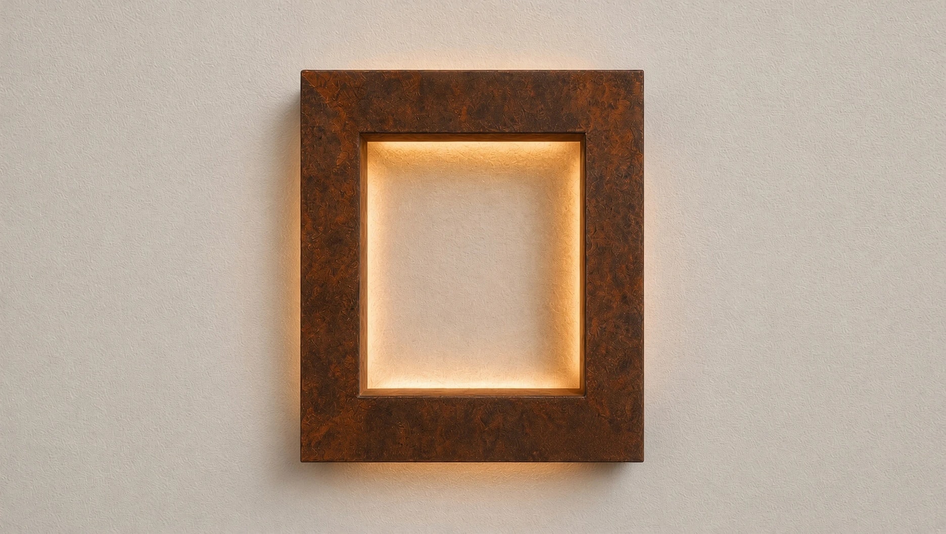 Applique carrée Aura en acier Corten éclairée, vue de face sur un mur clair