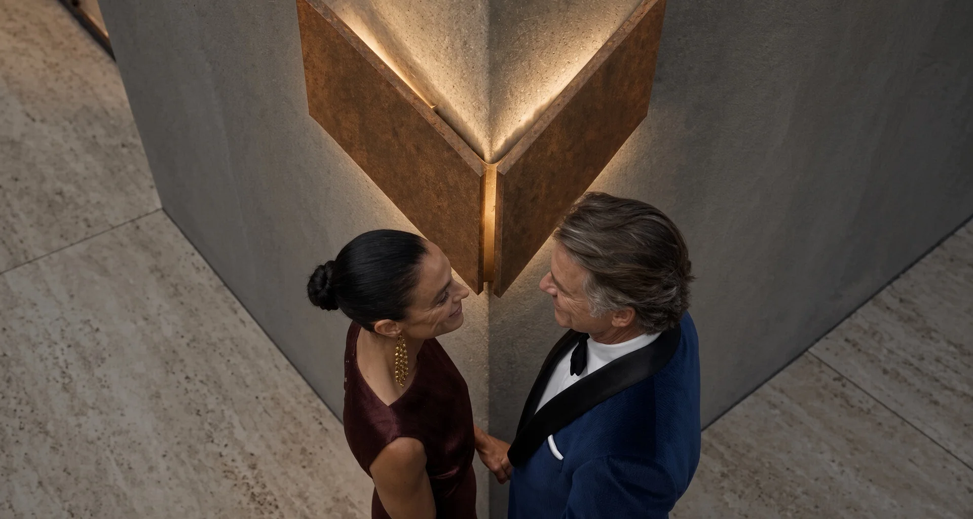 Applique Angle Dièdre en acier Corten vue en contre-plongée, au-dessus d'un couple en tenue de soirée