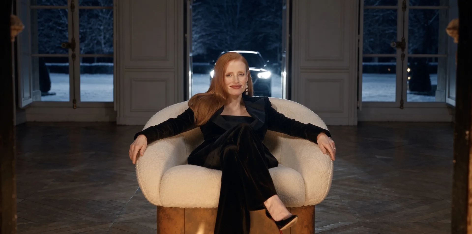 Fauteuil Hestia en acier Corten, une femme les bras posés sur les accoudoirs, phares d'une voiture derrière les fenêtres