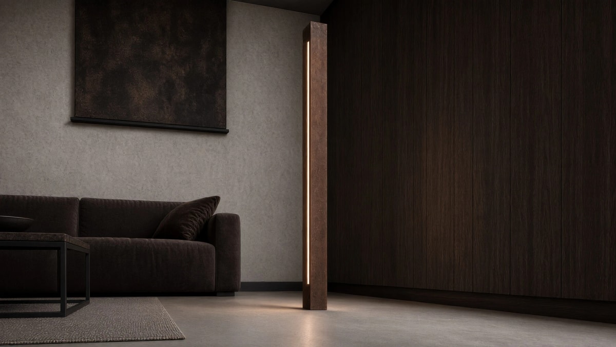 Lampadaire Sirius en acier Corten allumé contre une cloison en bois sombre, à côté d'un canapé
