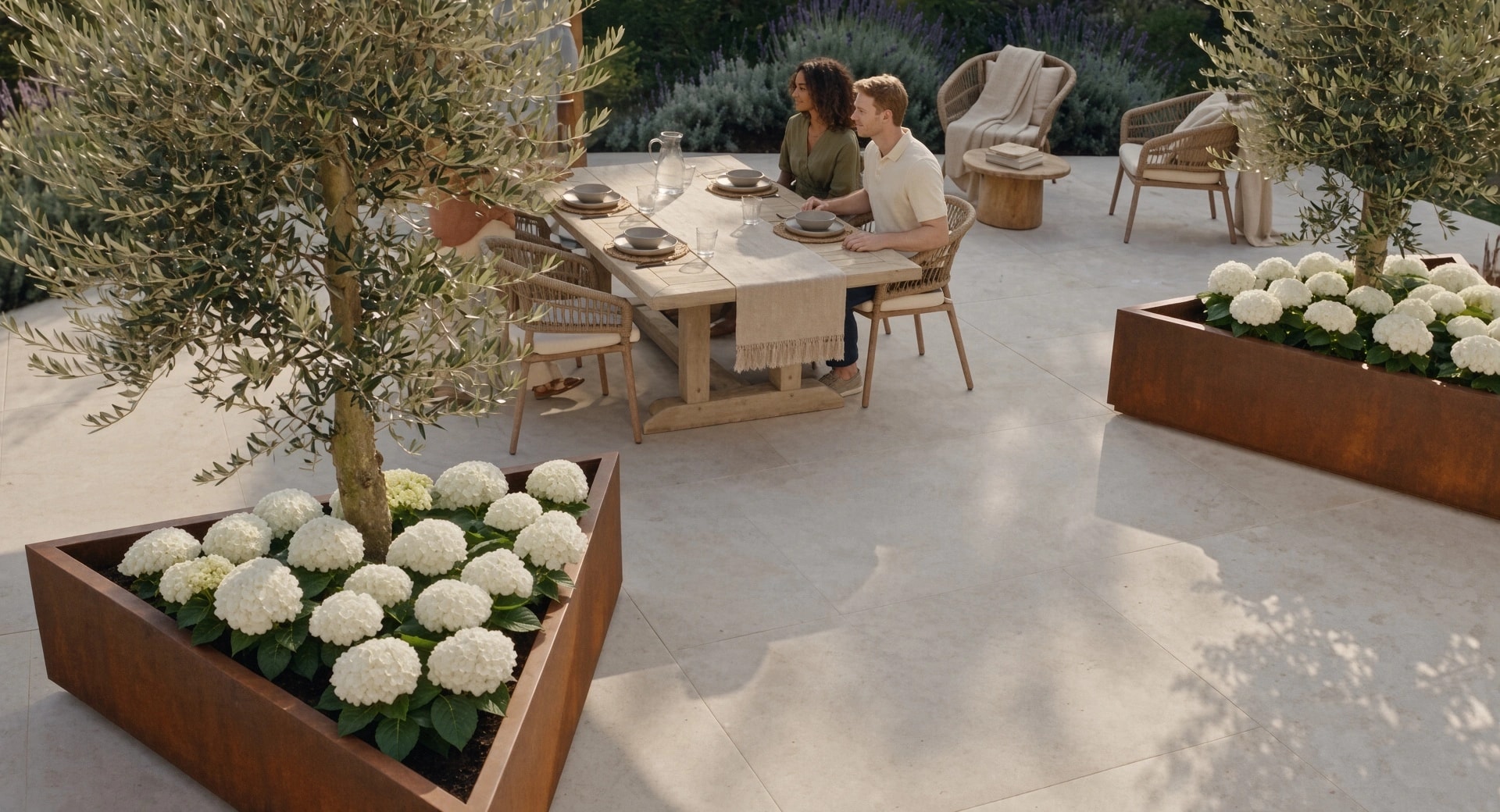 Jardinières triangulaires Iris en acier Corten avec oliviers autour d'une table où un couple est attablé, vue en plongée