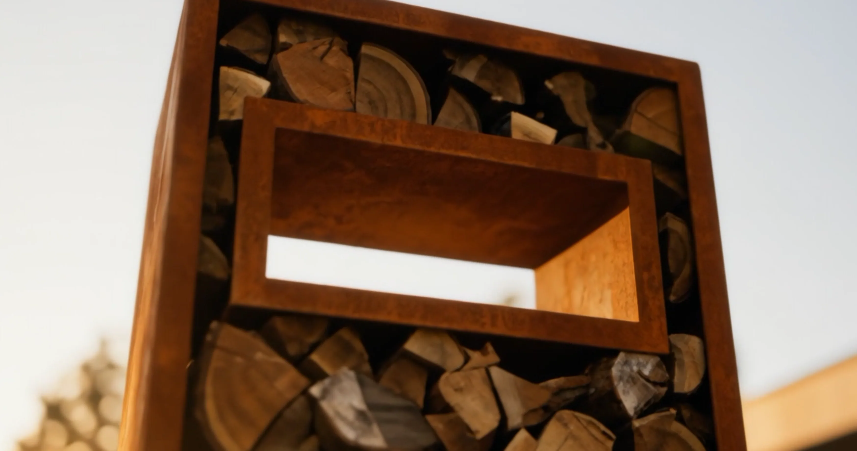 Module fenêtre rectangulaire Gemitus en acier Corten dans le haut d'un range-bûches, gros plan en contre-plongée