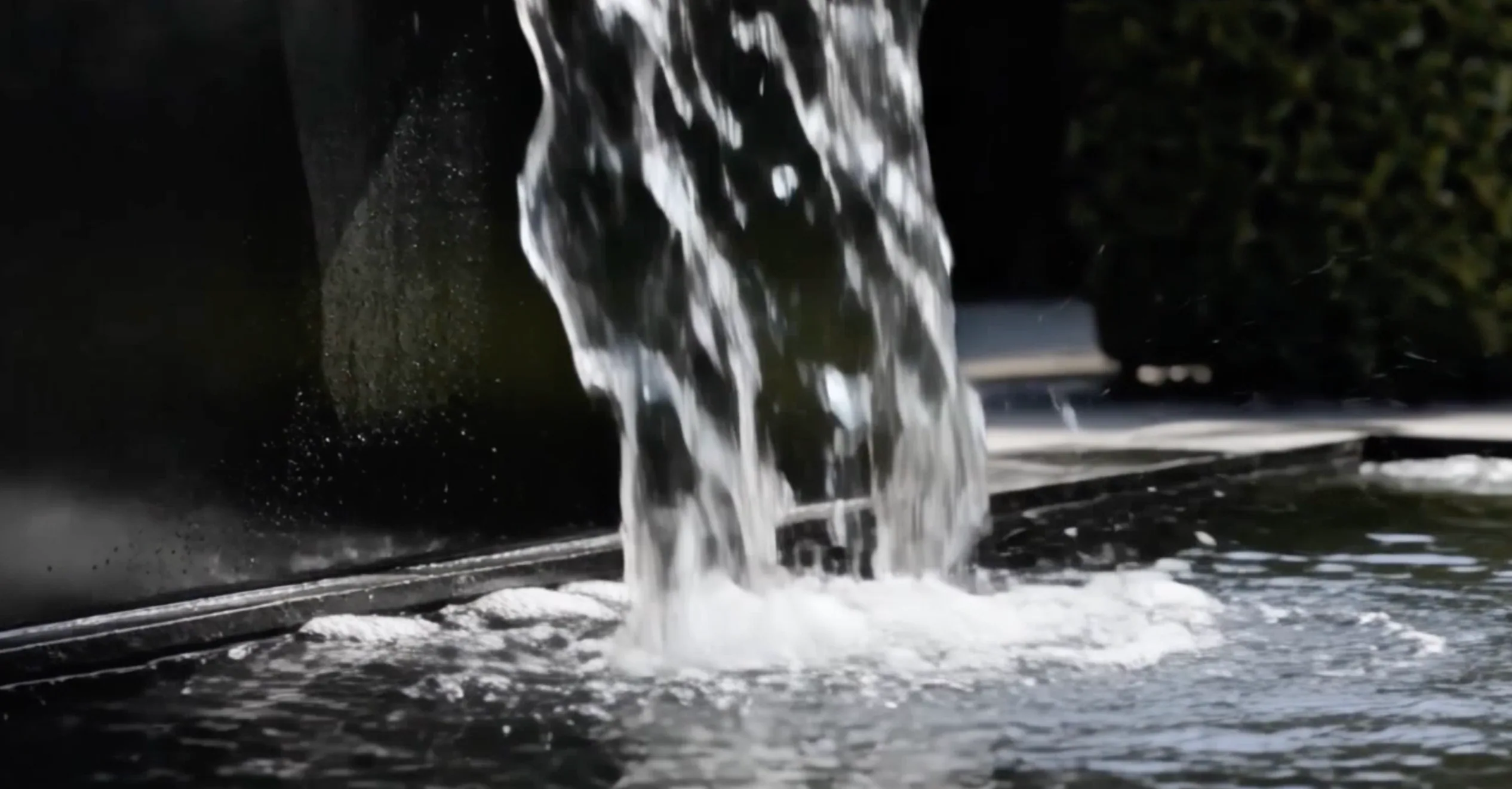 Détail de la chute d'eau du mur d'eau Léandre en aluminium éclaboussant la surface du bassin