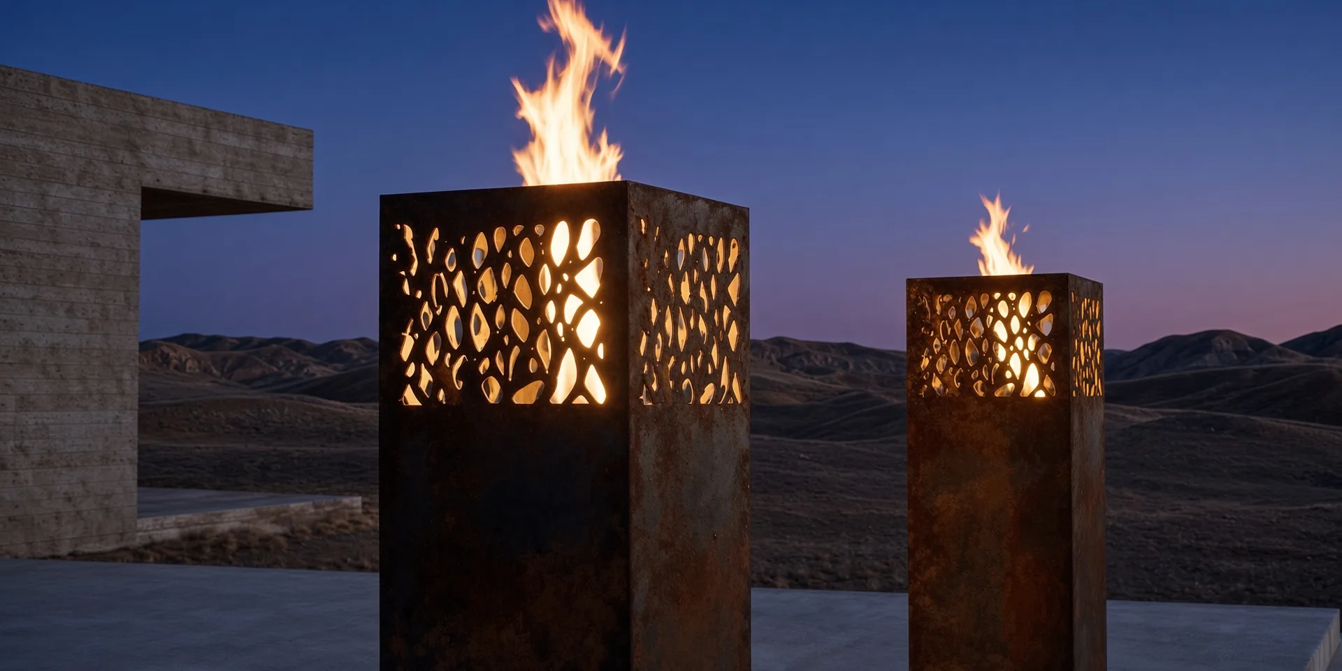 Deux lanternes Vesper en acier Corten allumées au crépuscule, face à des dunes de sable