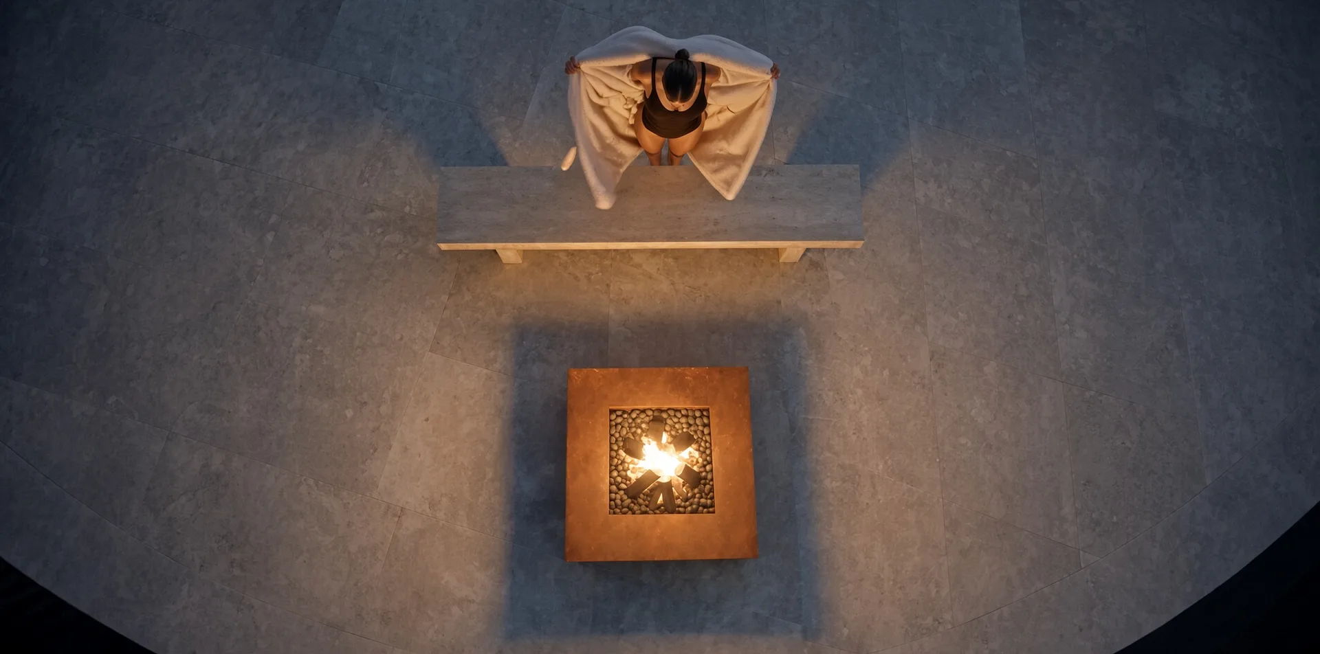 Vue de dessus de la table de feu Héphaïstos en acier Corten allumée de nuit, une personne assise sur un banc