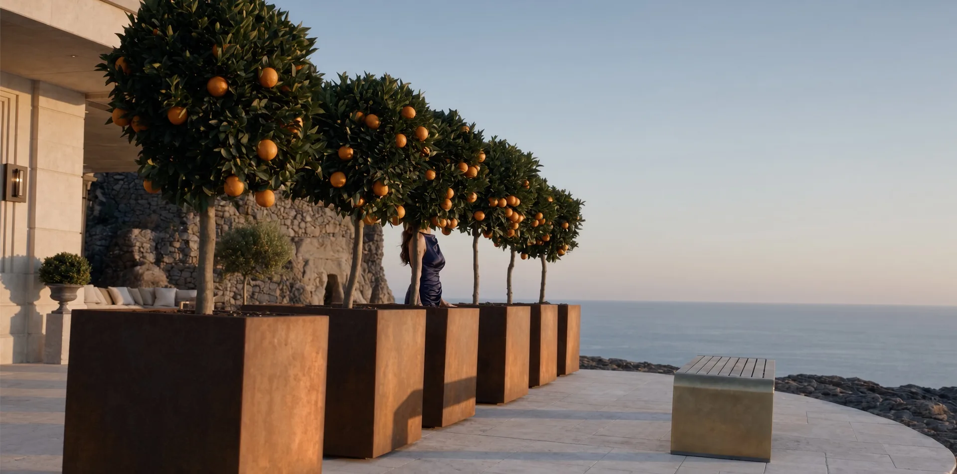 Perspective de jardinières carrées Cybèle en acier Corten avec orangers le long d'une terrasse dominant la mer
