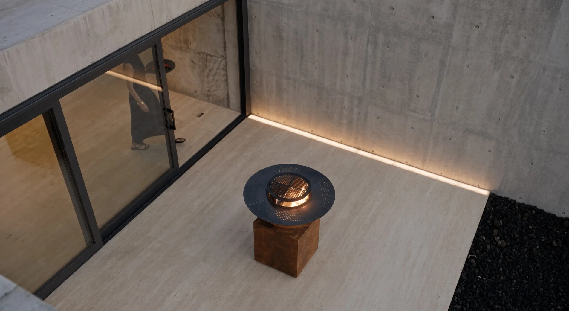 Barbecue Vulcain en acier Corten dans un patio en béton, vue plongeante près d'une baie vitrée