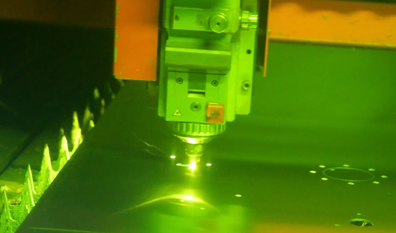 Laser cutting a metal sheet in the Cortenys workshop, sparks beneath the cutting head
