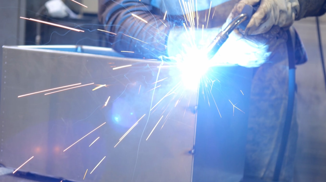 Arc welding the corner of a sheet-metal box in the Cortenys workshop, shower of sparks