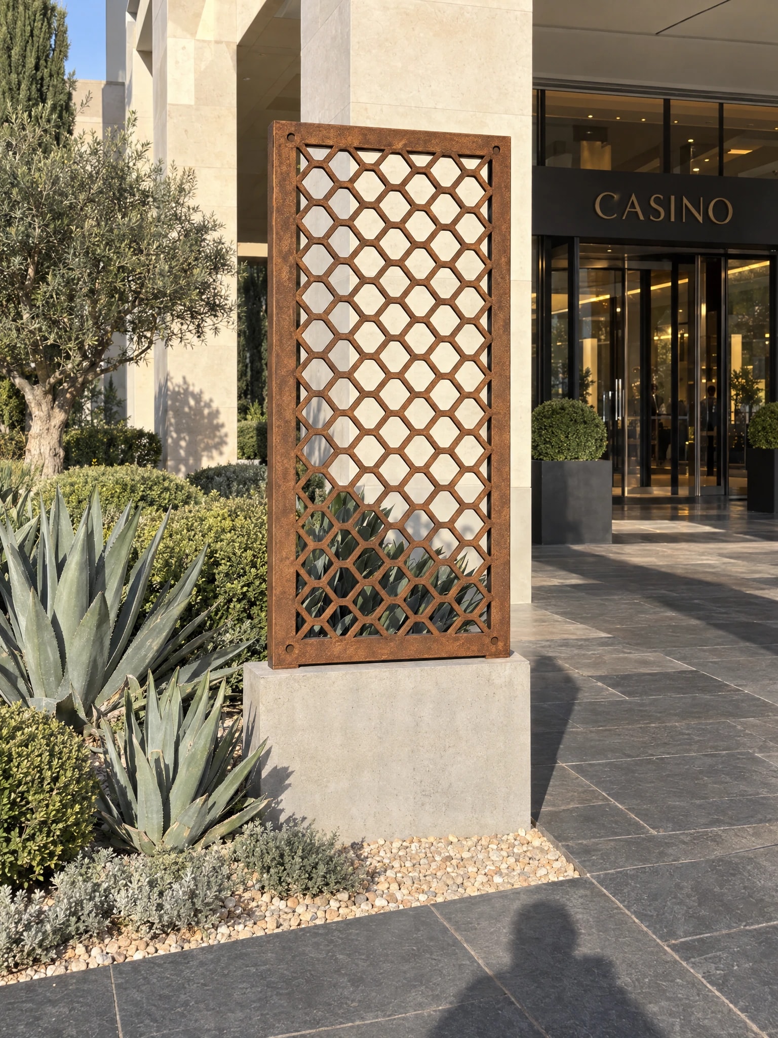 Panneau décoratif Levant en acier Corten sur un socle dans un massif d'agaves, devant l'entrée d'un casino