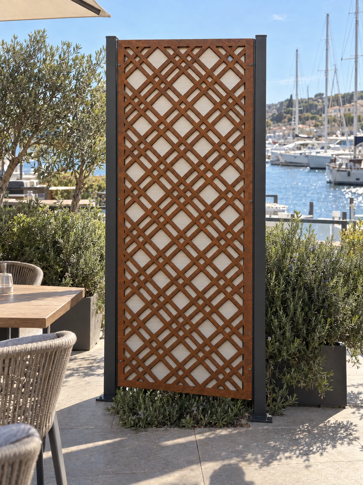 Panneau décoratif Tramontane en acier Corten entre deux poteaux sur une terrasse face à un port de plaisance